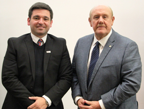 Two gentlemen in suits smiling at camera together